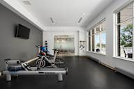 a workout room with a bike and other exercise equipment in a building with large windows at Verge Apartments in St. Louis Park, MN