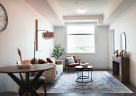 A living room with a couch, a table, and a clock on the wall.