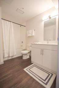 A white bathroom with a toilet, sink, and shower.