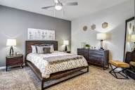 A bedroom with a large bed, a bench, and a ceiling fan.