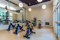 A room with a row of stationary bikes.