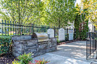 A gated entrance with a stone wall and a metal gate.