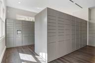 A wall of lockers in a room with wood flooring.