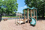 A playground with a green slide and wooden structure.