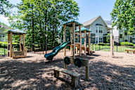 A playground with a green slide and a wooden bench.
