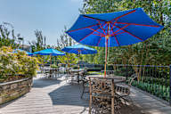 A blue umbrella is in the foreground of a wooden deck.