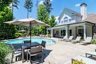A pool with chairs and an umbrella in front of a house.