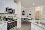 A kitchen with a stove, microwave, and a dining table with chairs.