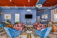 Bloomingdale Woods Apartments Valrico Florida Clubhouse Interior with 2 Couches, 2 Lounge Chairs, High-Top Tables with Chairs and Decorative Coffee Tables and Lighting with TV