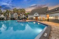 A swimming pool in front of a house with a sunset in the background.