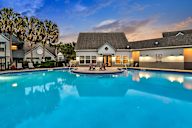A swimming pool in front of the Leasing Clubhouse rear exit with modern pool furniture.