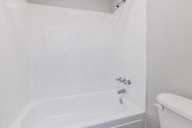 White bathroom with a tub and a toilet.