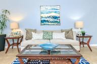 Living room with a white couch, a blue coffee table, and a painting on the wall.