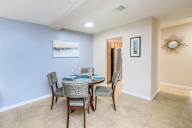 Dining room with a table set for two and a painting on the wall.