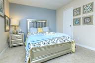 Bedroom with a bed, nightstand, lamp, and wall art.