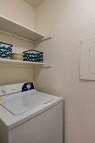 A white washing machine sits in a small laundry room.