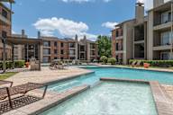 A large outdoor pool with a hot tub in front of apartment buildings.