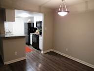 A kitchen with black appliances and a wooden floor.