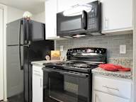 A black refrigerator and microwave in a kitchen with white cabinets.