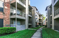 Long concrete walkway separates the grassy areas of apartment buildings.