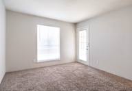 Room with a carpeted floor, a window, and a door.