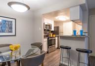 A modern kitchen with a glass table and bar stools.