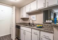 A kitchen with white cabinets and a granite countertop.