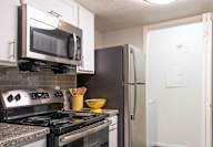 A kitchen with a stove, microwave, and refrigerator.