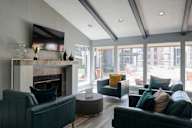 A living room with a fireplace and a television mounted above it.