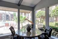 A dining table with chairs in front of a window with a view of a pool and buildings outside.
