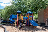 A playground with a blue and yellow slide and a red and yellow structure.