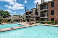 A large swimming pool in front of a multi-story apartment building.