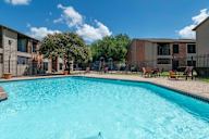 A swimming pool in a sunny day surrounded by chairs and trees.