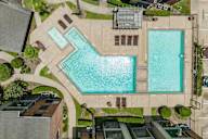 A large swimming pool surrounded by a concrete patio and a small building.
