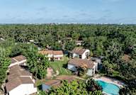 Bird's eye view of a residential area with houses, trees, and a swimming pool.