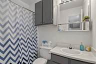 A bathroom with a sink, toilet, and a shower with a chevron patterned shower curtain.