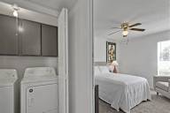 A bedroom with a bed, a chair, and a washing machine.