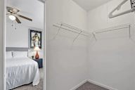 A bedroom with a bed, a ceiling fan, and a picture on the wall.