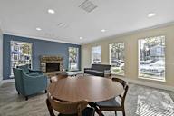 A room with a fireplace and a table surrounded by chairs.