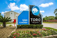 A sign for Toro Fondren Place with a blue house and a bear logo.