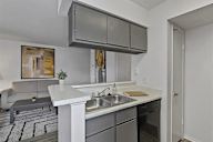 A modern kitchen with a white countertop and grey cabinets.