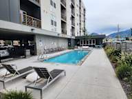 A pool area with sun loungers and a building in the background.