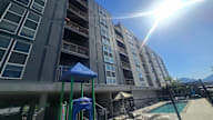 A sunny day at a playground in front of a large apartment building.