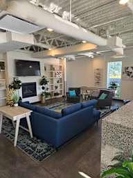 A living room with a blue couch and a television on the wall.