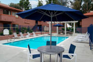 a patio with a table and umbrella next to a swimming pool