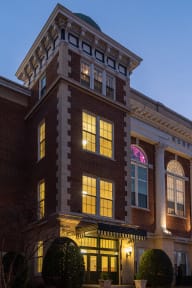 a red brick building with a white trim and a pink neon sign in the window