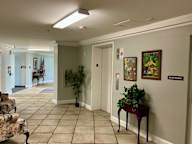 A hallway with a plant on a table and a framed picture on the wall.