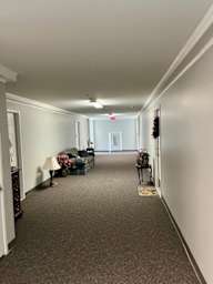 A hallway with a lamp, a sofa, and a chair.