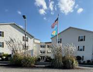 A white building with an American flag and a blue flag with white stars on it.