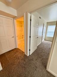 A hallway with a carpeted floor and white walls.